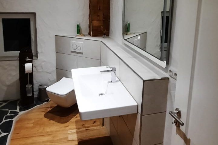 Modernes Badezimmer mit Waschbecken, WC und Holzfußboden.
