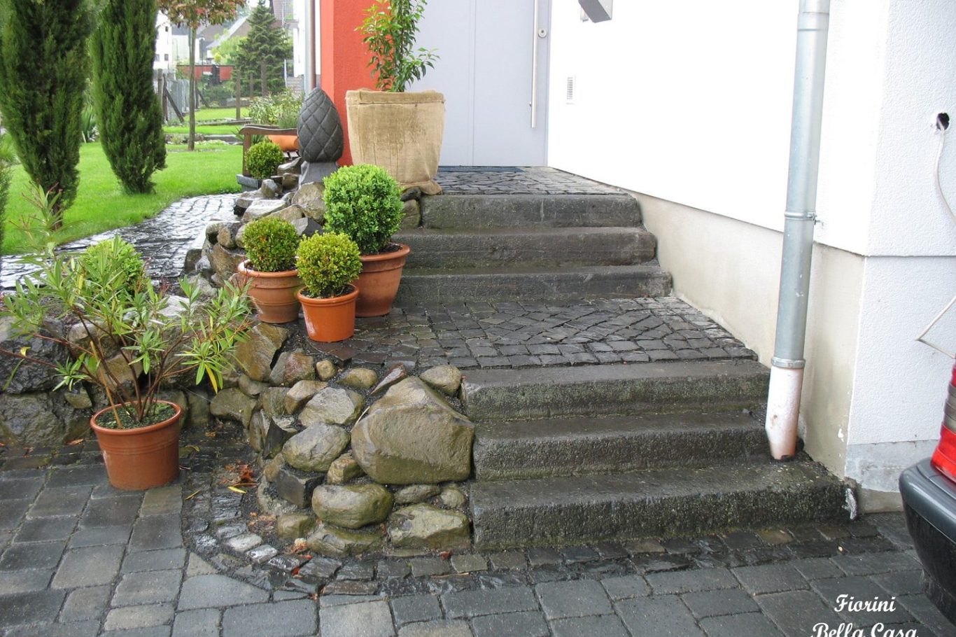 Steinerne Treppe mit blühenden Pflanzen in Töpfen neben einem Haus.