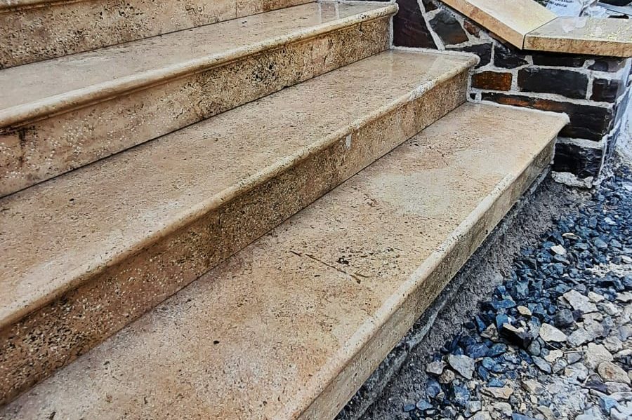Beige Treppenstufen aus Travertin auf einer unvollendeten Baustelle.
