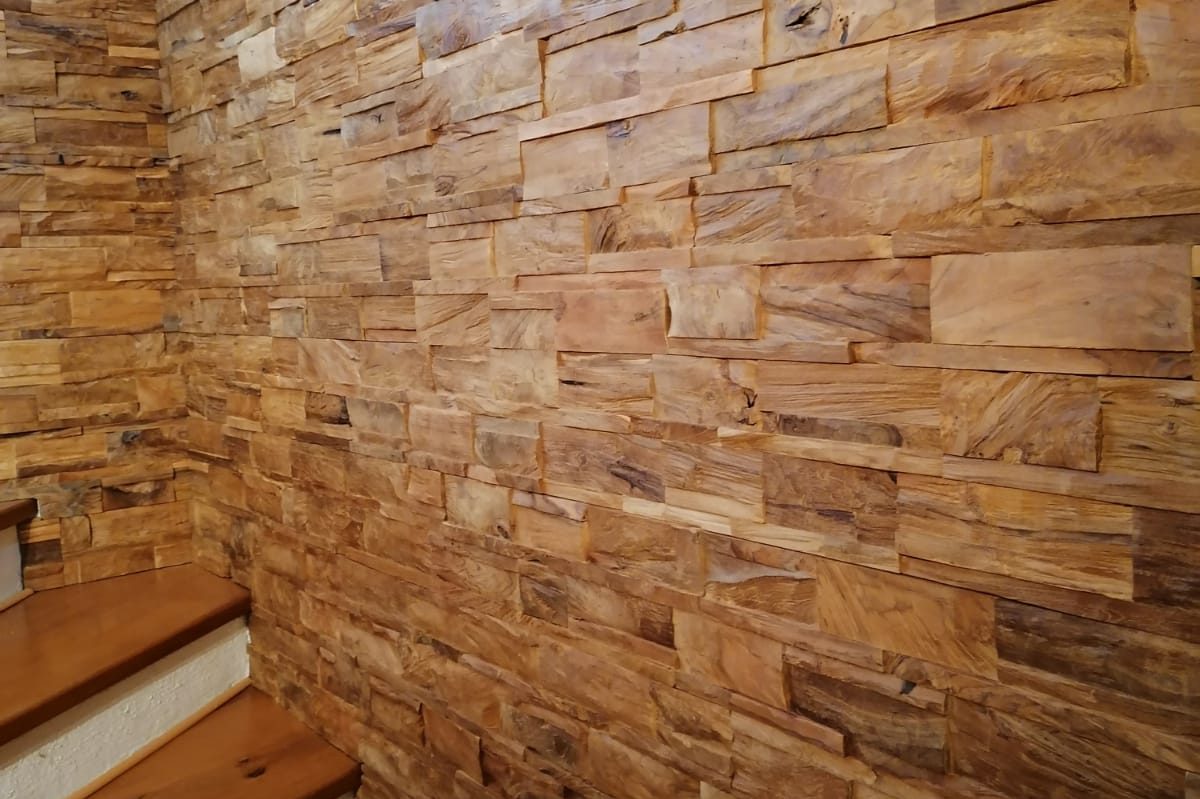 Rustikale Steinwand mit gemischten Holzsteinchen und einer Treppe aus Holz.