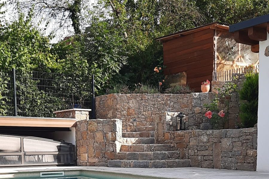 Muschelkalktreppe mit Garten und Holzschuppen neben einem Pool.